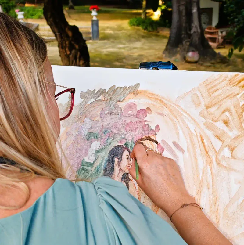Live wedding painting in progress as Marta adds fine detail to the couple’s portrait outdoors