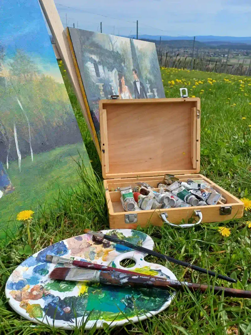 Plein-air live wedding painting setup with easel, oil paints and palette at a Spanish wedding