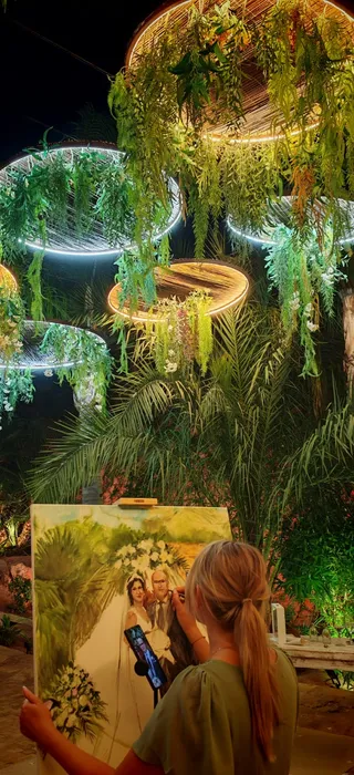 Live wedding painter Marta painting a portrait of the newlyweds at an elegant greenery-filled venue on the Costa del Sol