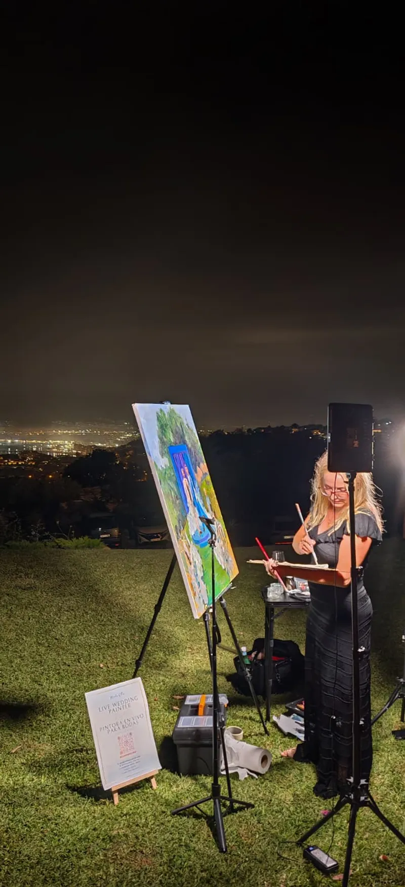 Marta painting live at an evening hilltop wedding above the city lights of the Costa del Sol
